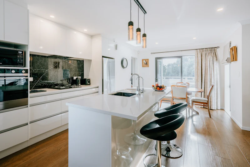 Clean white kitchen with an island and a dining table by the window